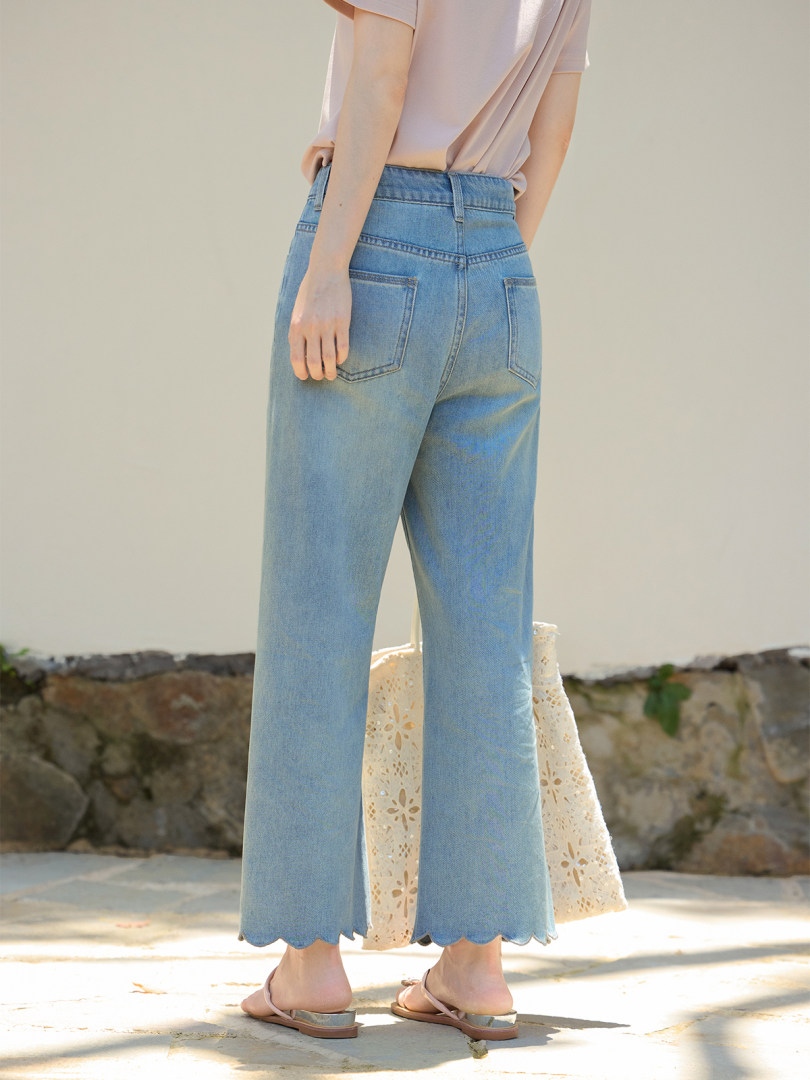Model wearing light blue high-waisted jeans with scalloped hems