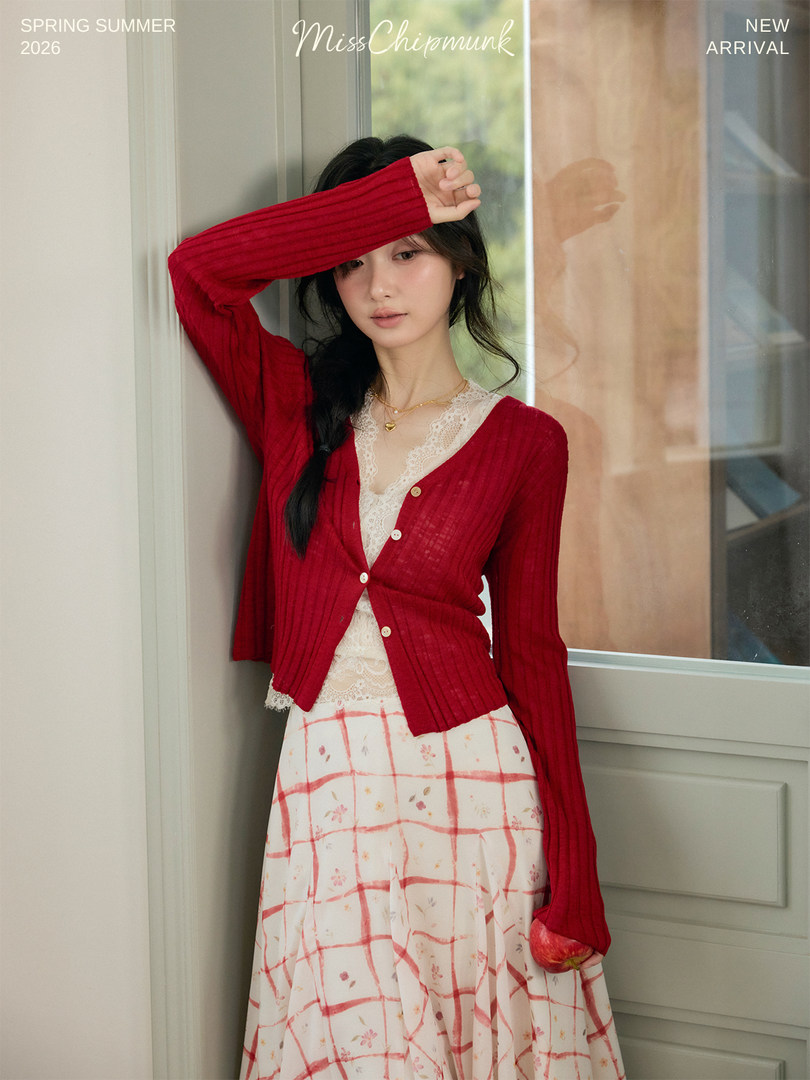 Woman wearing a red cardigan over a lace top with a patterned skirt