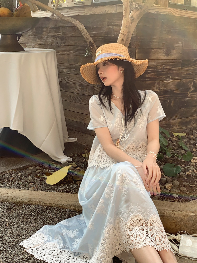 Woman wearing a light blue lace dress and straw hat outdoors