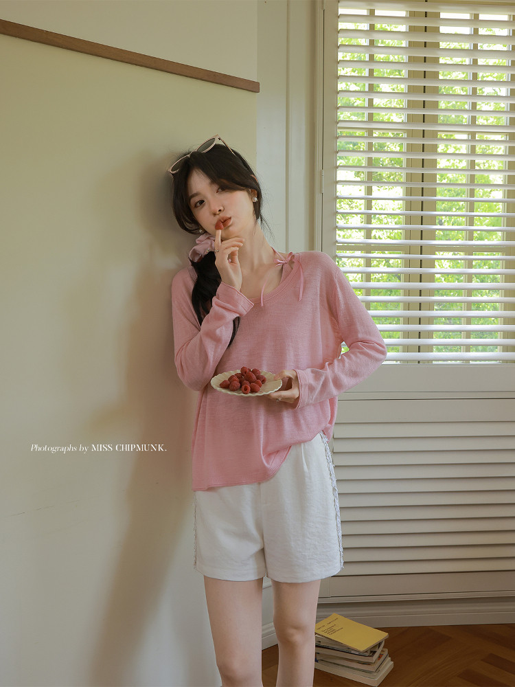 Model wearing a pink long-sleeve top with white shorts indoors