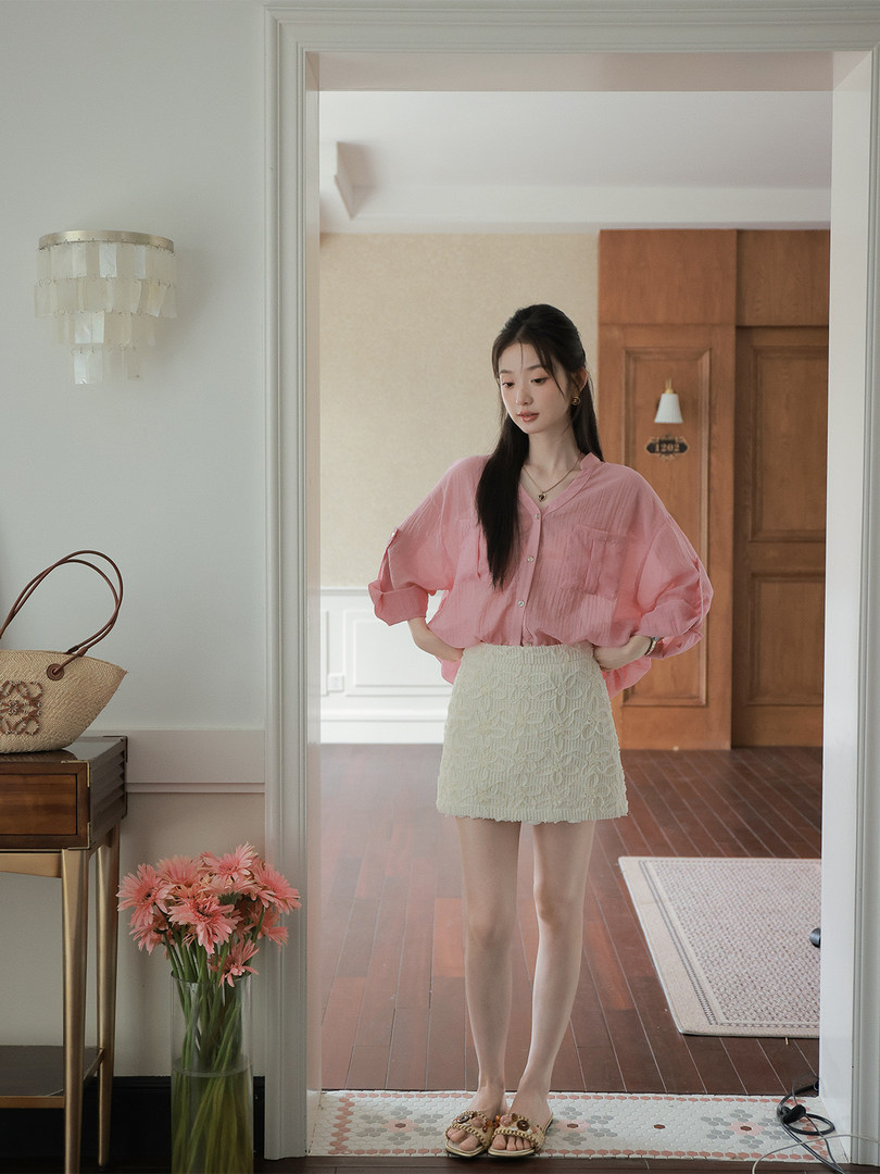 Woman wearing a pink blouse with a cream textured mini skirt