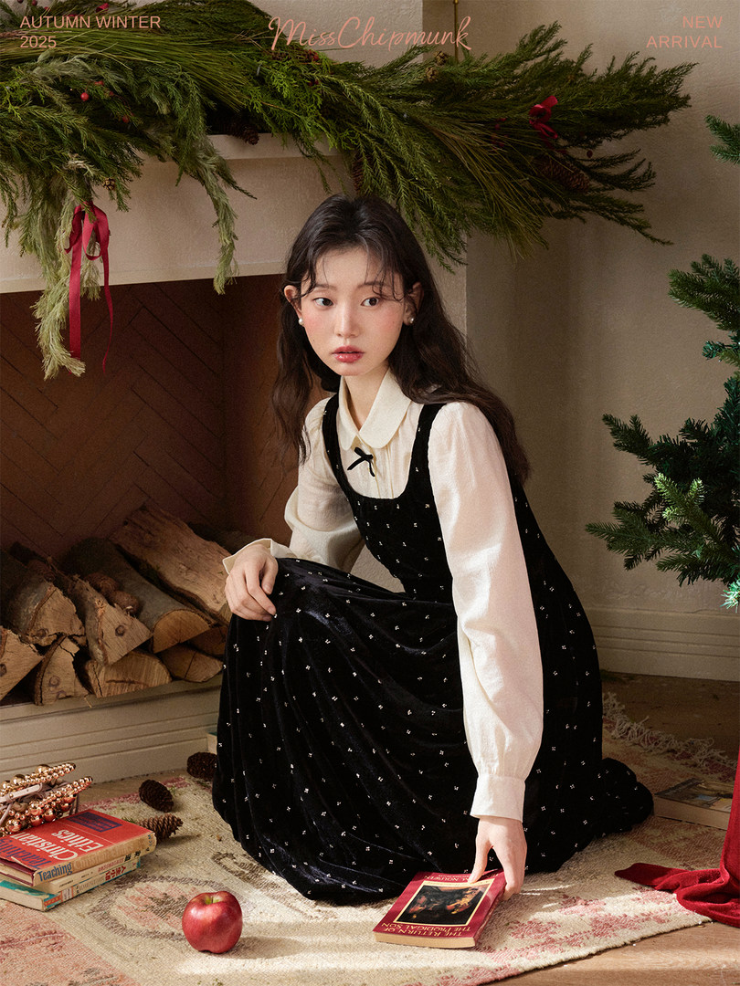 Model wearing a black velvet dress over a white blouse in a winter holiday setting