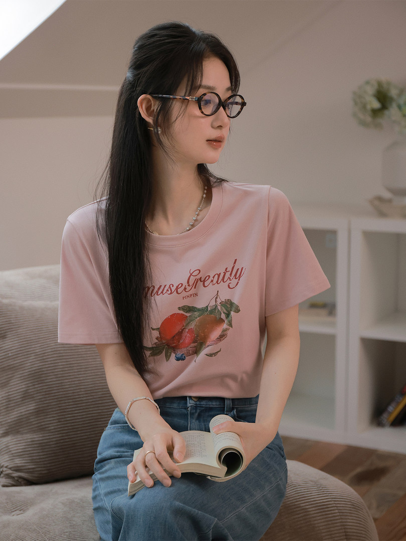 Woman wearing a pink graphic T-shirt with fruit print and blue jeans