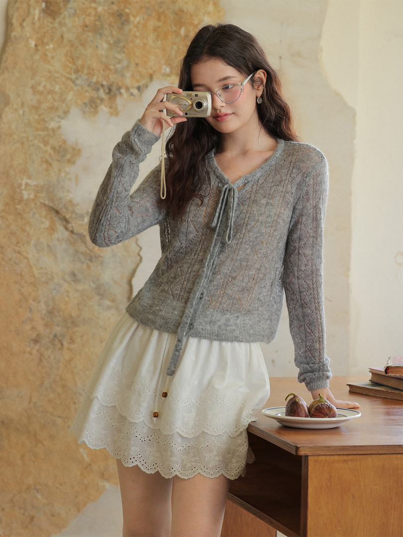 Model wearing a gray knit cardigan with a white layered skirt