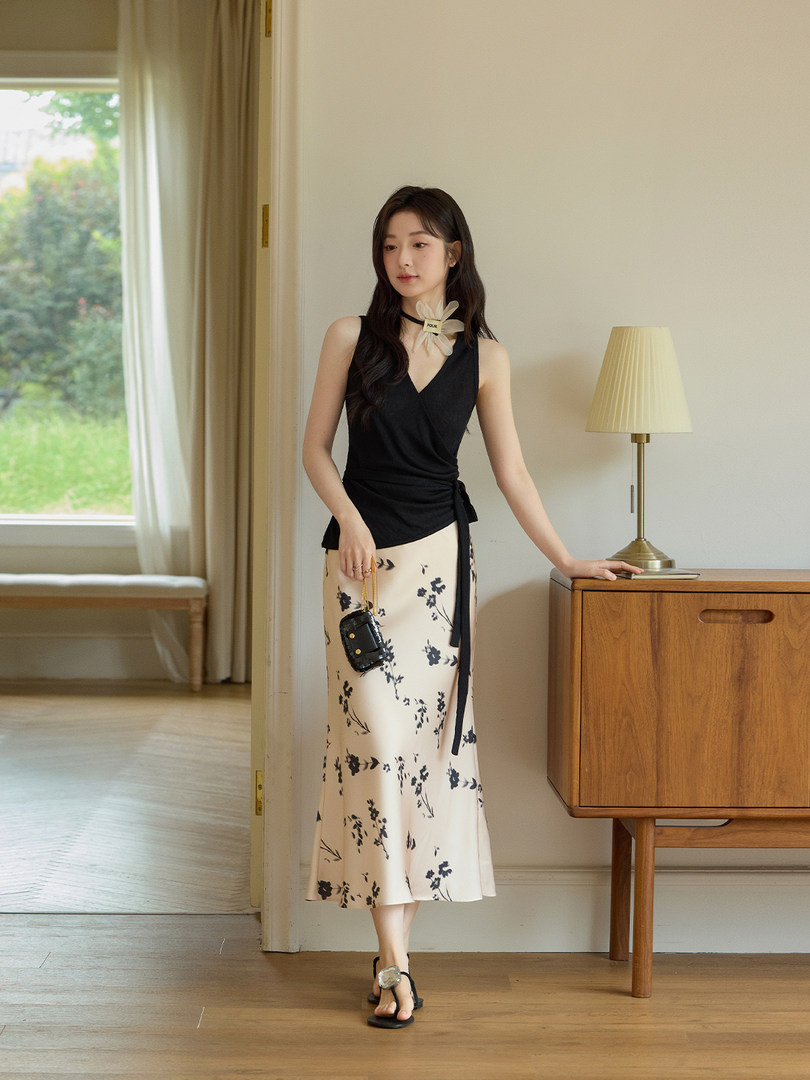 Model wearing a black sleeveless wrap top with a floral midi skirt