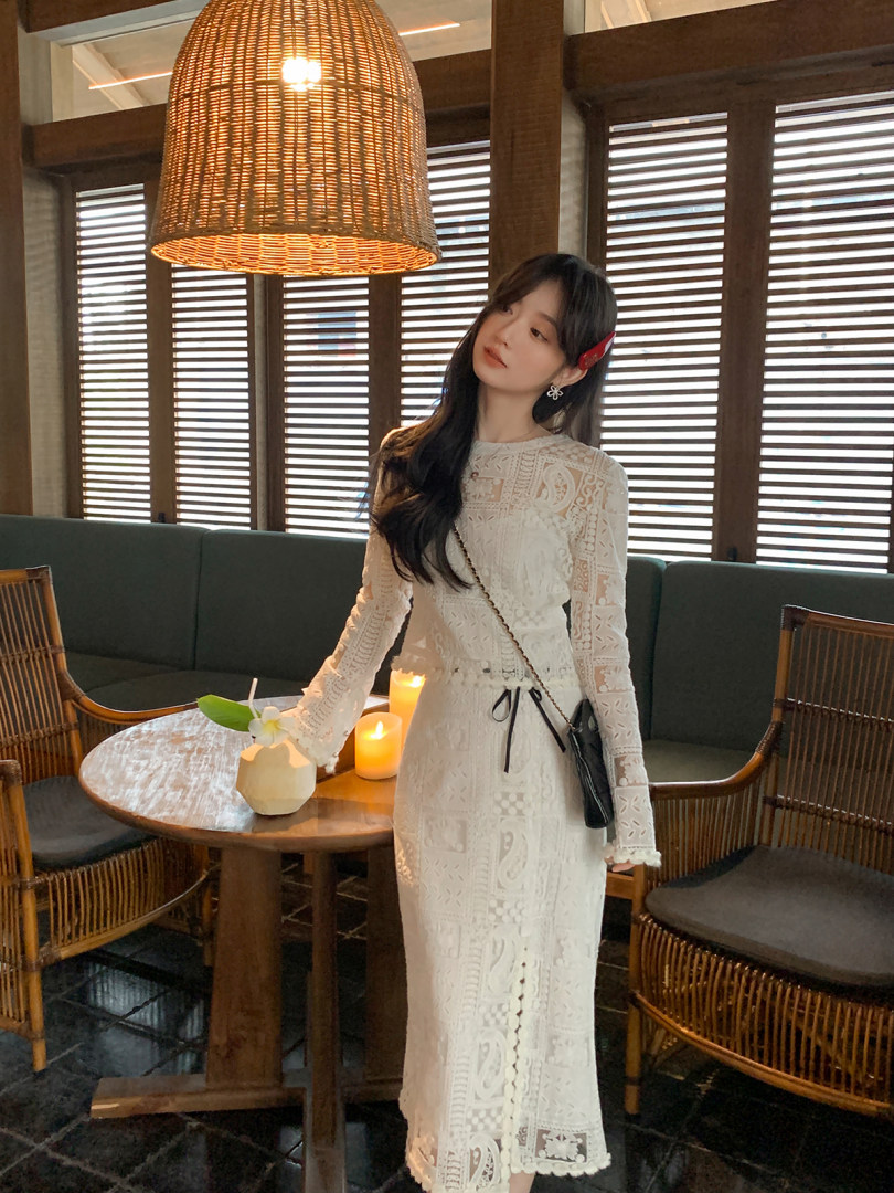 Woman wearing a white lace long-sleeve dress in a restaurant setting