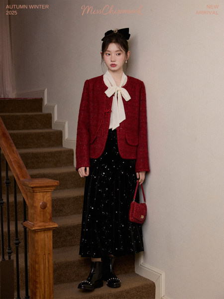 Model wearing a red jacket, white bow blouse, and black star-pattern skirt with boots and handbag