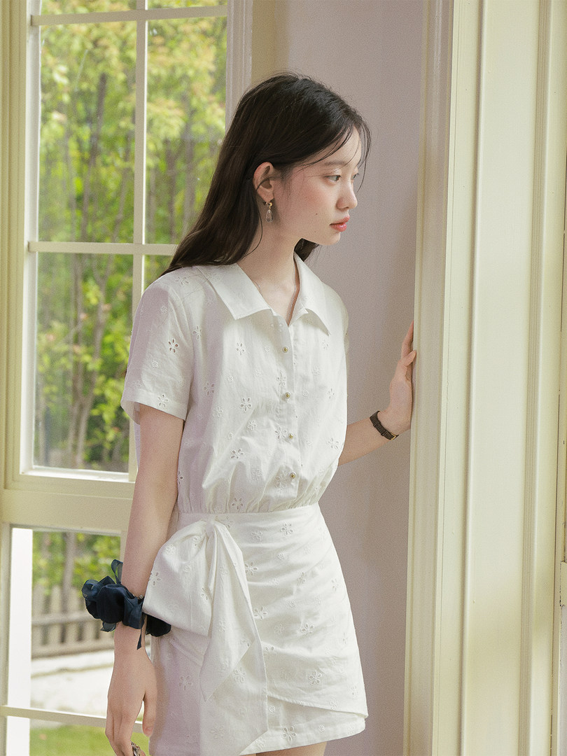 White short-sleeve embroidered wrap dress worn by a model indoors