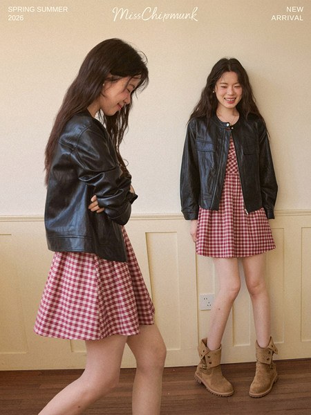Model wearing a black leather jacket over a red gingham dress with boots
