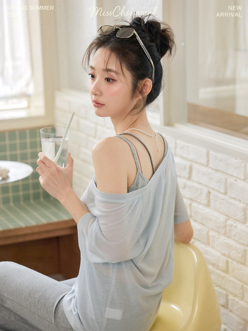 Model wearing a light blue sheer off-shoulder top over a tank top