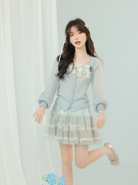 Model wearing a light blue floral knit cardigan with a sheer ruffled skirt