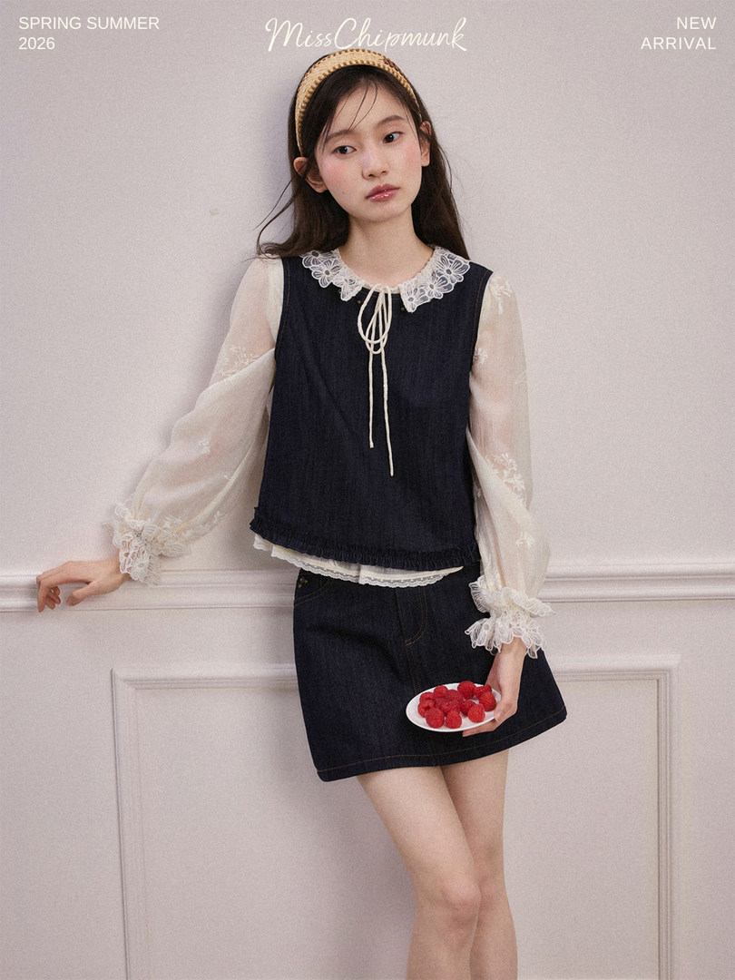 Model wearing a navy dress layered over a sheer lace blouse