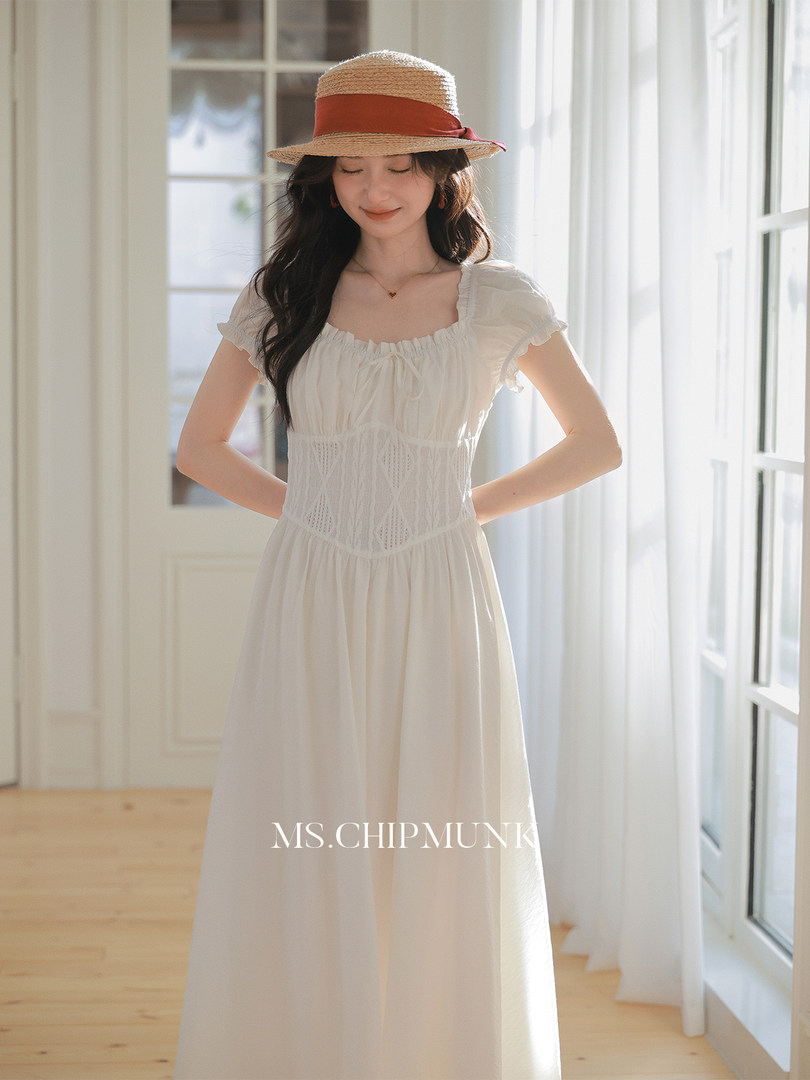 Woman wearing a white lightweight dress with a straw hat