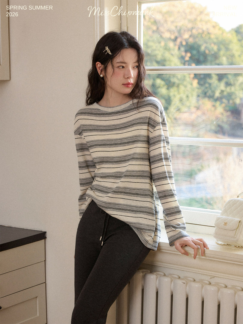 Model wearing a striped long-sleeve top with black pants indoors