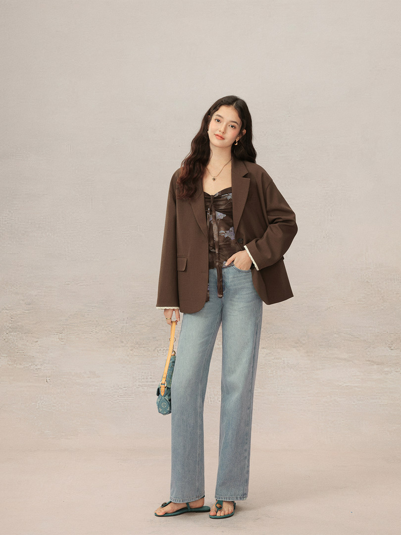 Woman modeling a brown blazer with light blue jeans and green sandals