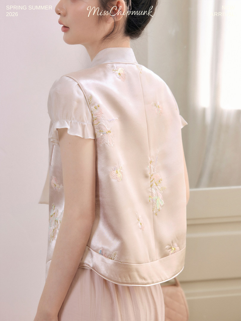 Woman wearing a pastel satin embroidered vest and blouse set