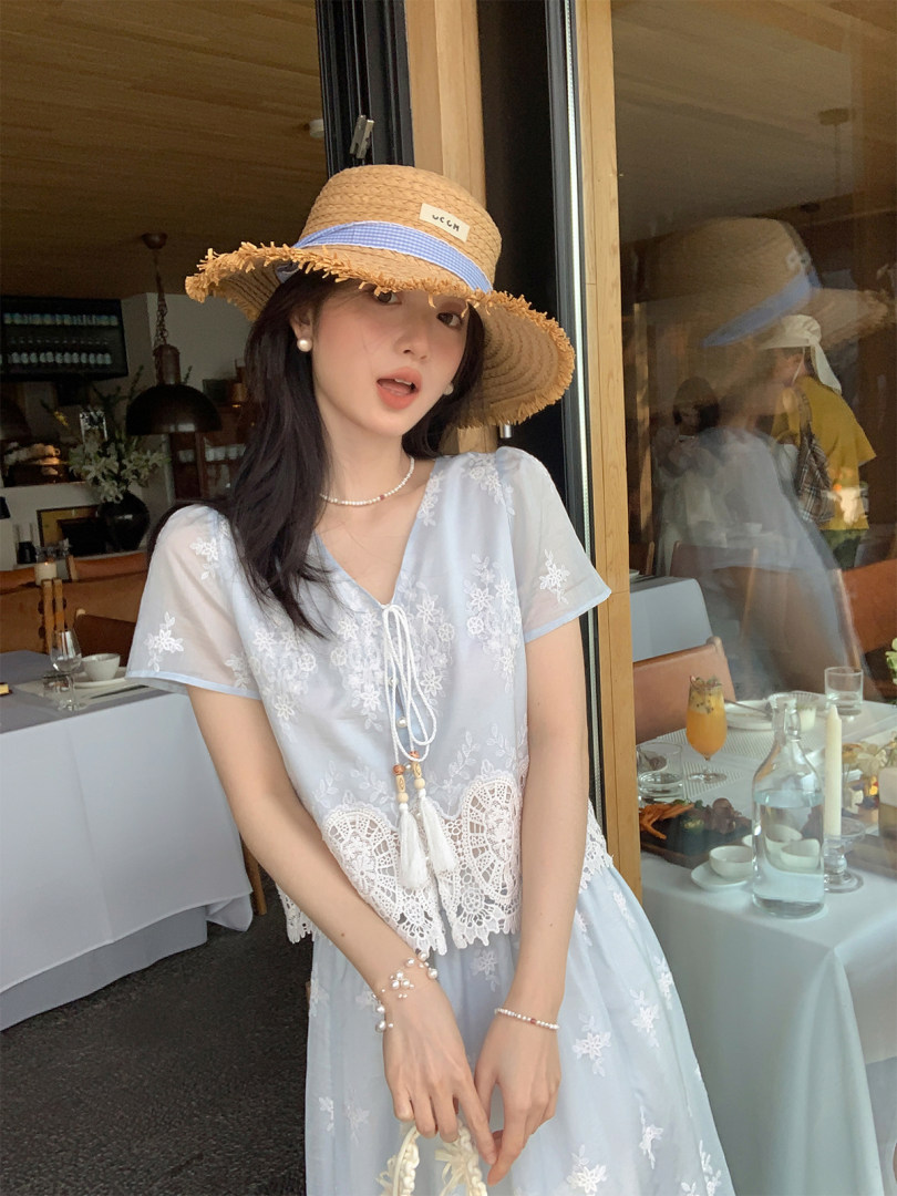Woman wearing a light blue embroidered dress with a straw hat