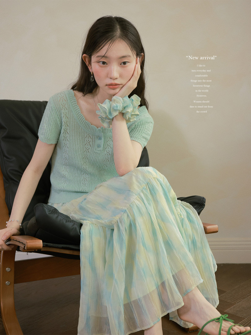 Model wearing a mint knit top and pastel sheer skirt
