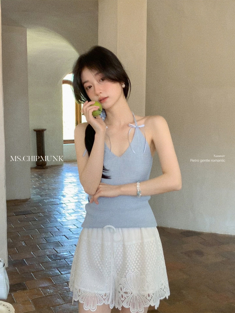 Model wearing a light blue knit halter top with a white lace mini skirt