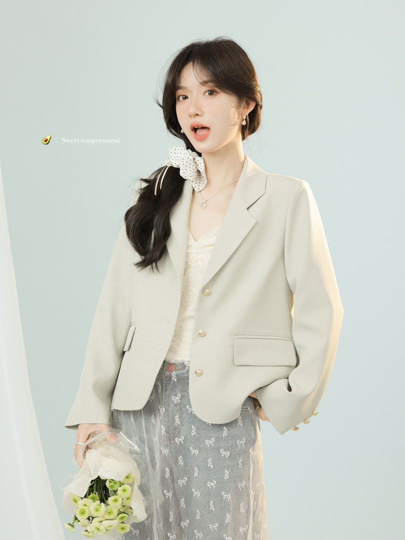 Woman wearing a light beige blazer with a sheer bow-pattern skirt