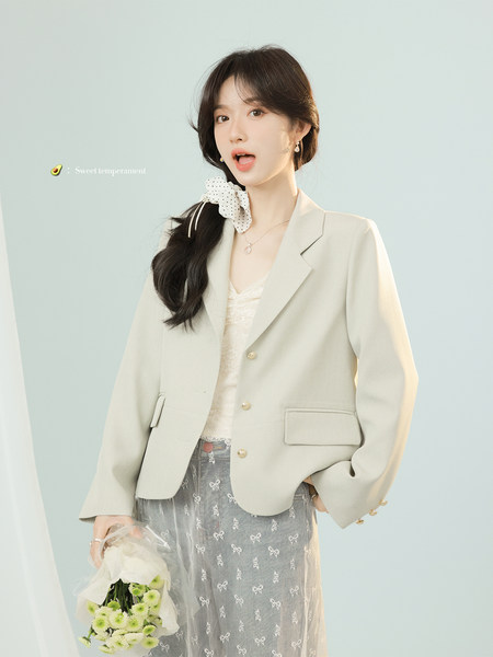 Woman wearing a light beige blazer with a sheer bow-pattern skirt