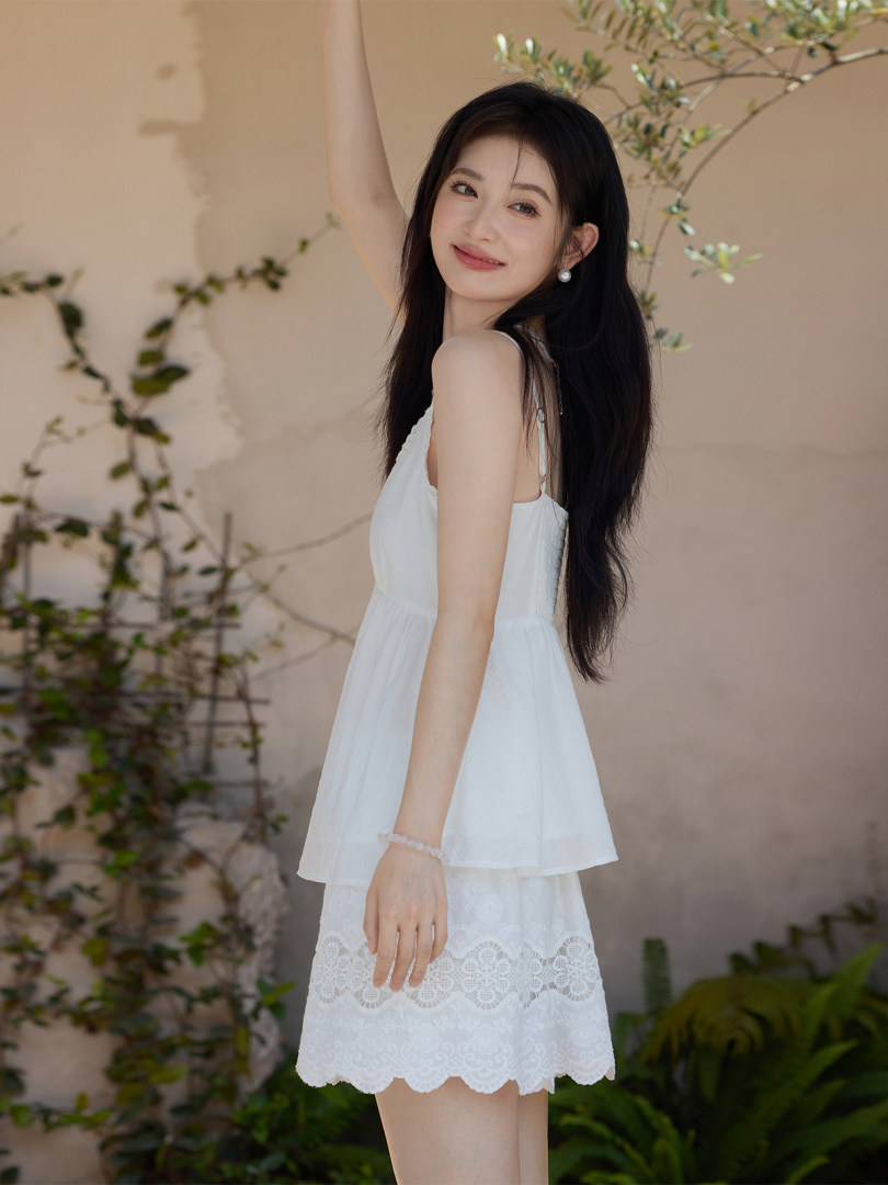 Woman wearing a white sleeveless lace-trim dress outdoors