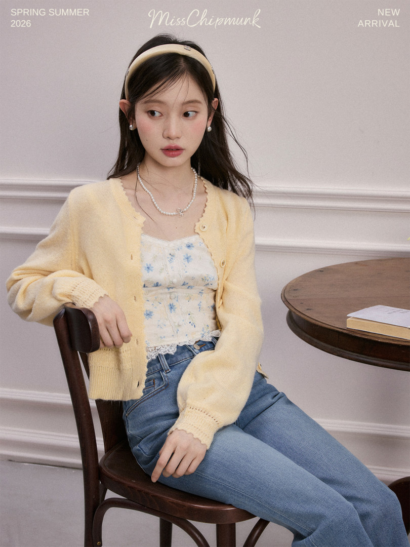 Model wearing a pale yellow cardigan over a floral camisole and blue jeans