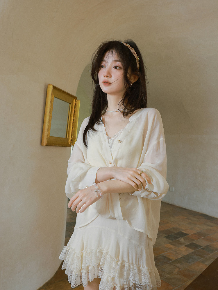 Woman modeling a white feminine lace dress with a sheer blouse