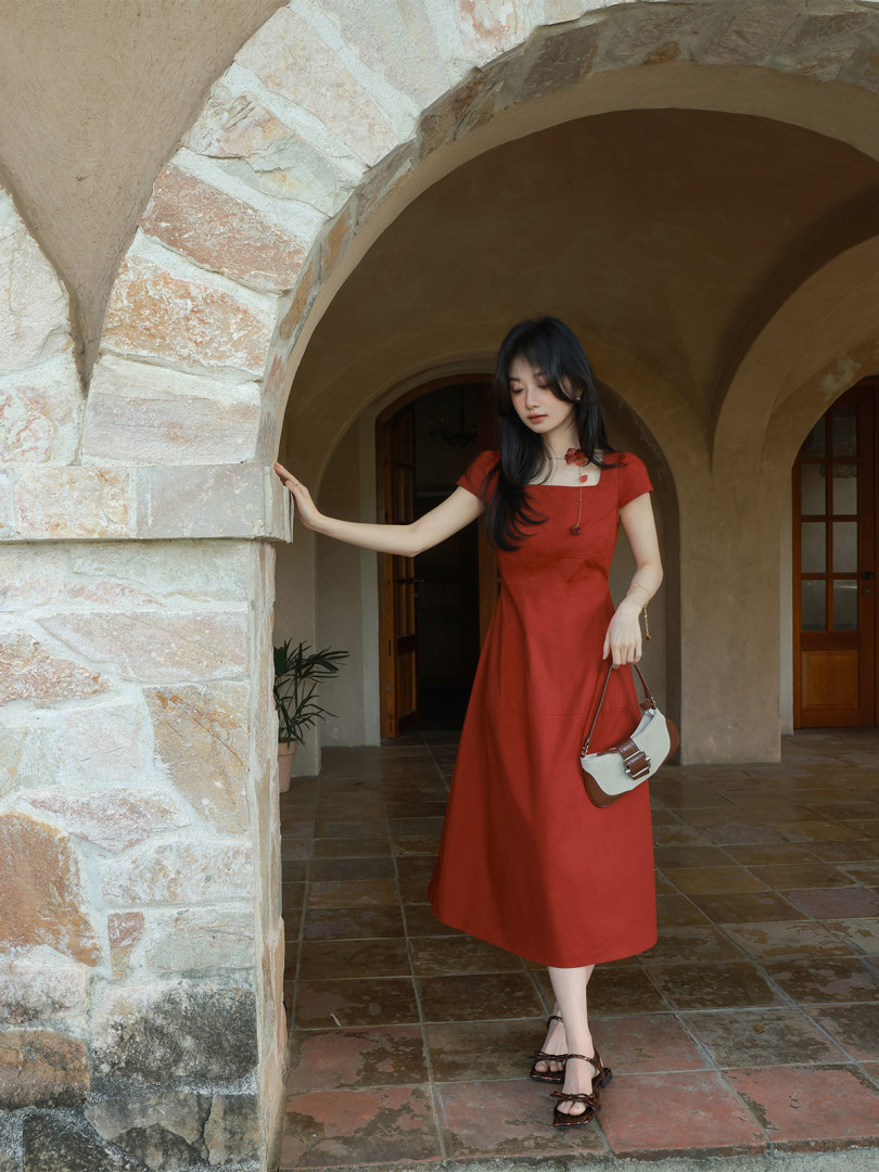 Woman wearing a red midi dress and holding a small handbag