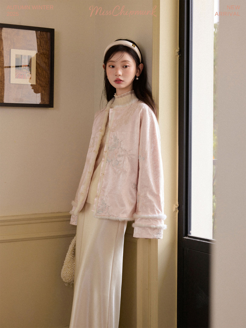 Model wearing a pale pink velour jacket with cream wide-leg pants in an indoor fashion photo