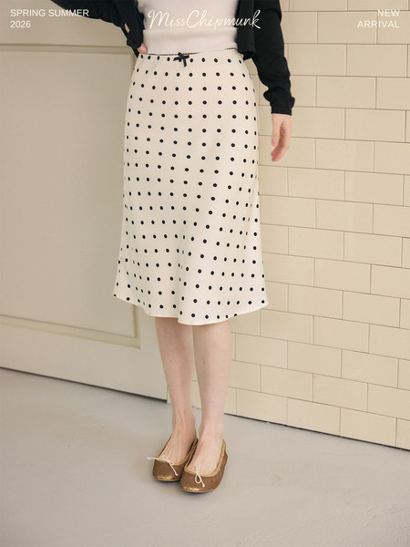 Model wearing a white polka dot skirt with black top and flats