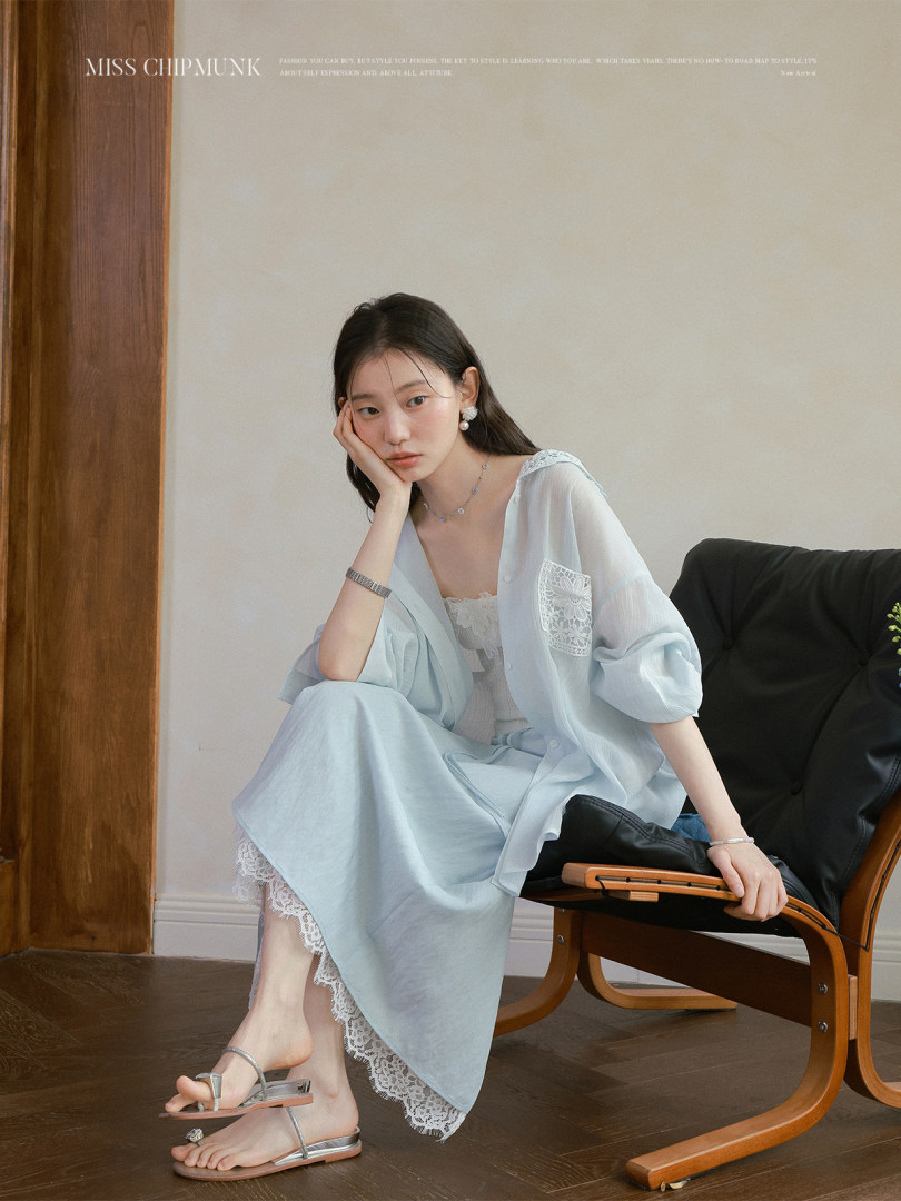 Model wearing a light blue sheer blouse and lace-trimmed skirt set