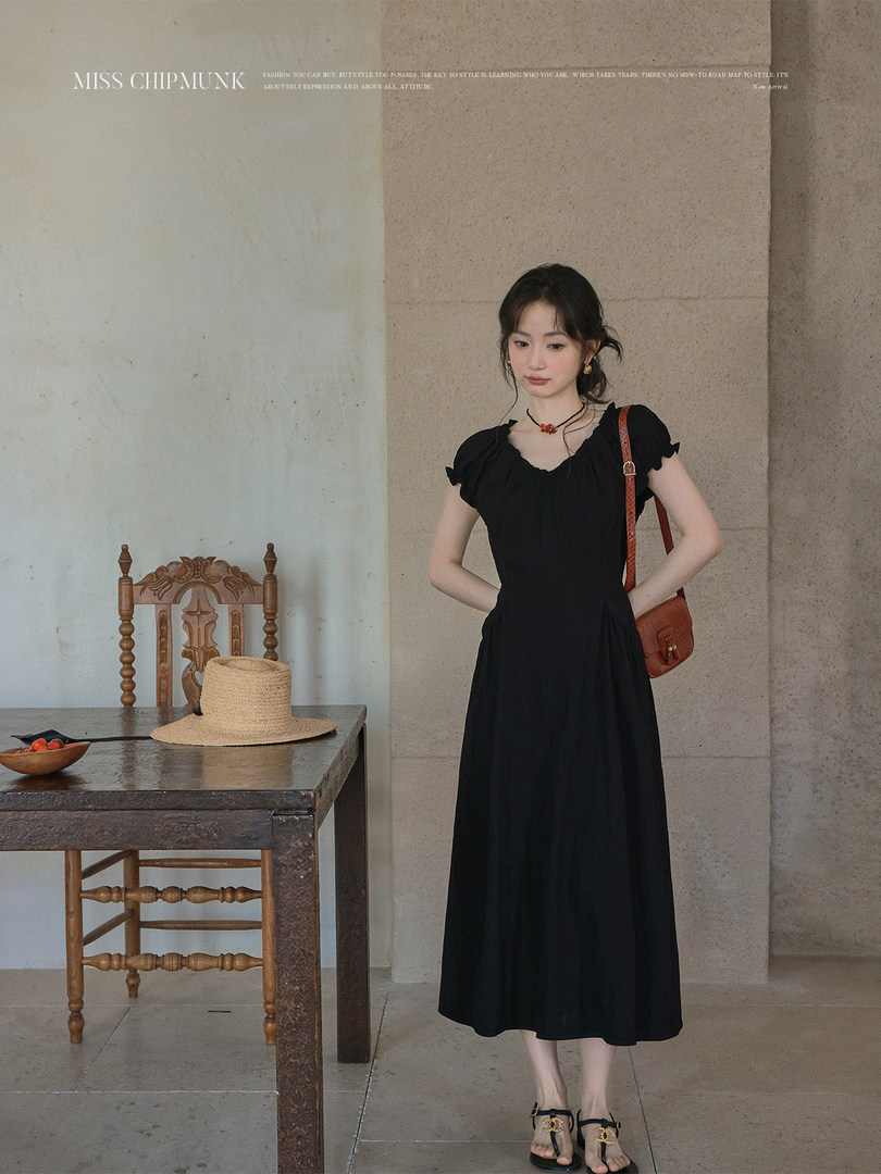 Black midi dress worn by a model with a small shoulder bag