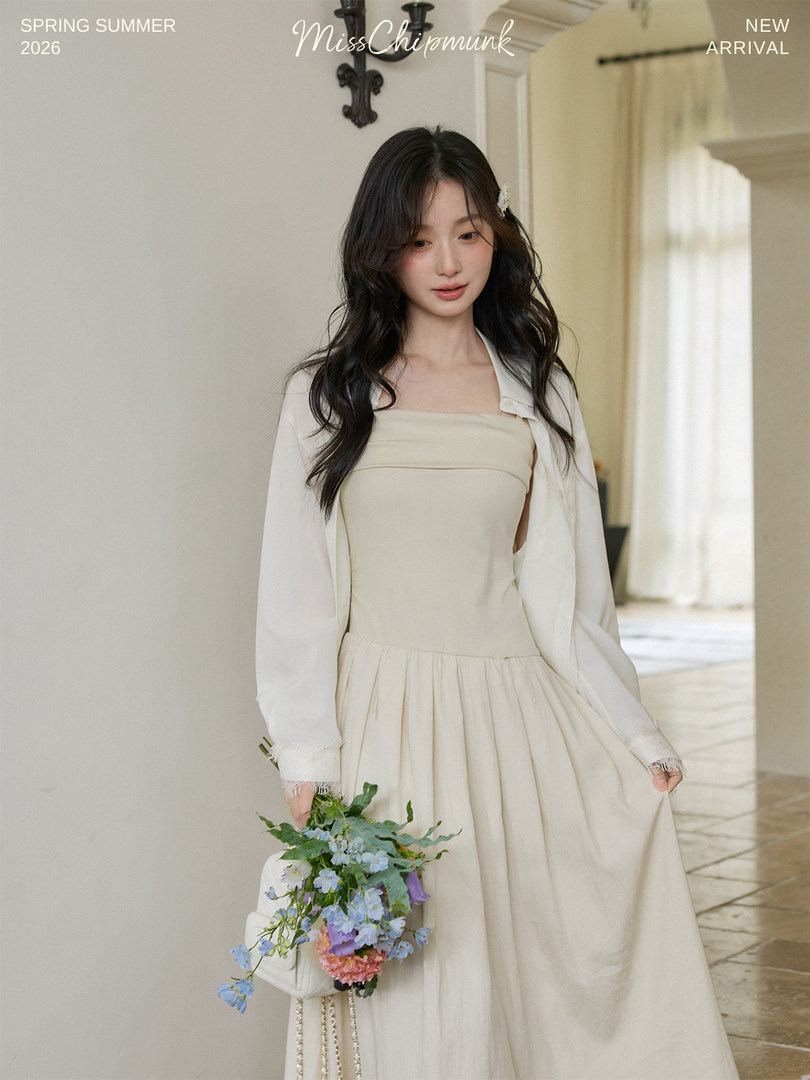 Model wearing a cream strapless dress with a white shawl and holding flowers
