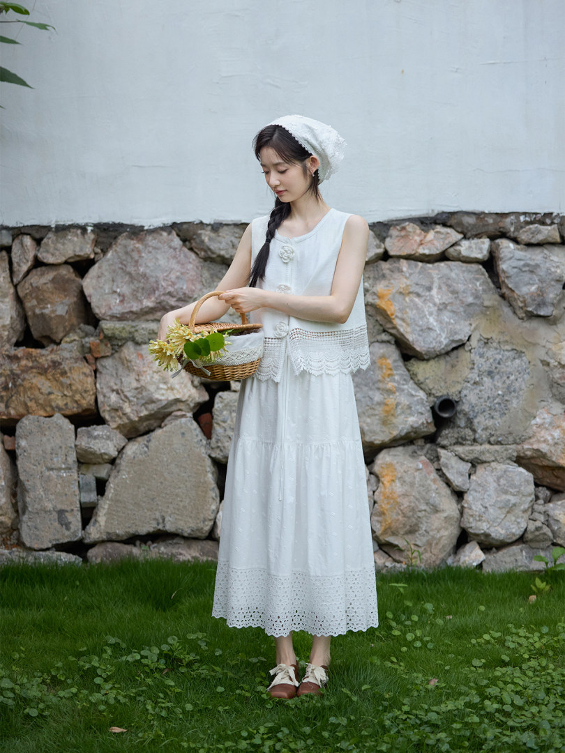 Woman wearing a white lace sleeveless dress and matching bonnet while holding a woven basket