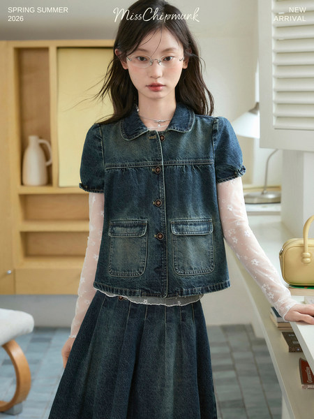 Model wearing a dark denim short-sleeve jacket and matching pleated skirt