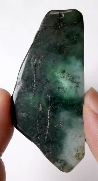 缅甸A货翡翠随形吊坠，似山形、梯形，较为别致。做工一般，抛光不细致，可能故意做成复古的斑驳之状，成为特立独行的腰佩挂饰。灯光照射下有一定透度。