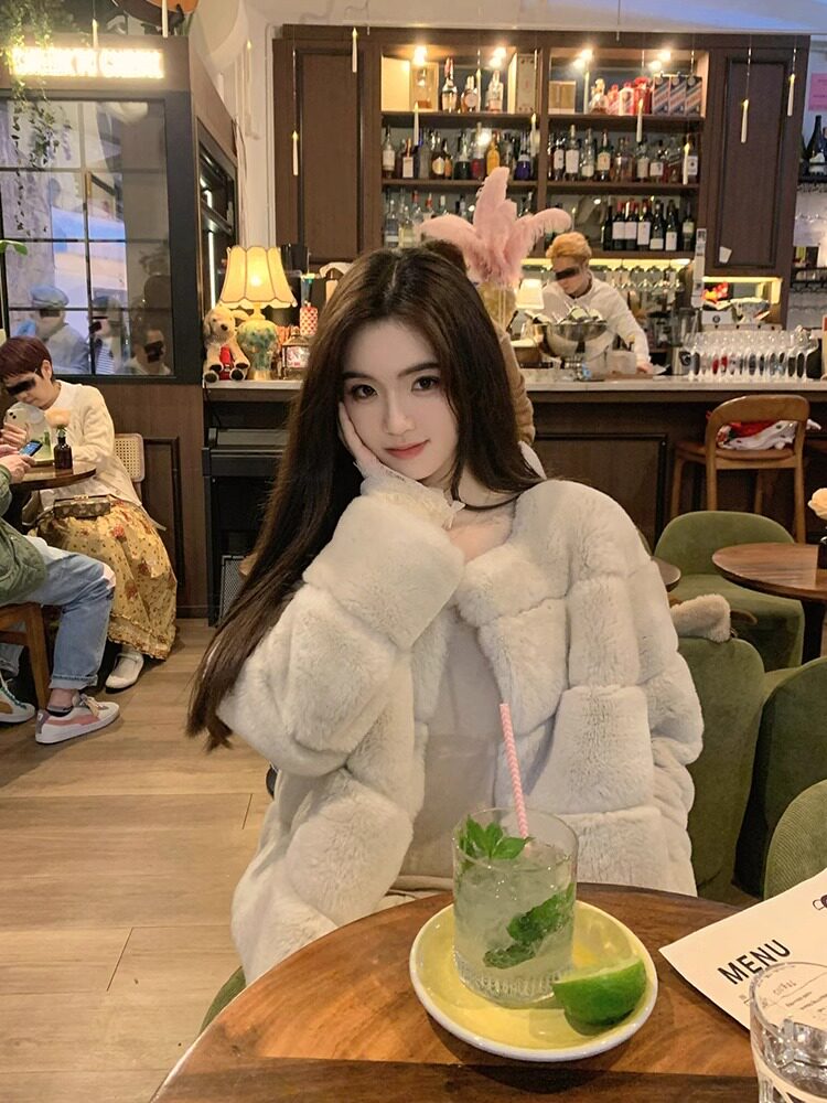 Woman wearing a white fluffy coat in a cafe setting