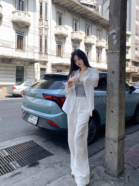Woman wearing white linen pants and white shirt standing on city street