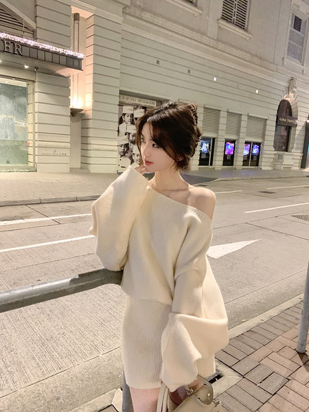 Woman wearing off-shoulder cream sweater and matching skirt on a city street at night
