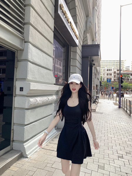 Woman wearing a black dress and white cap on a city street