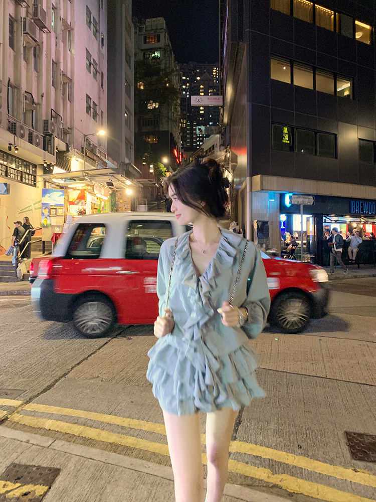 Woman wearing a light blue ruffled dress on a city street at night