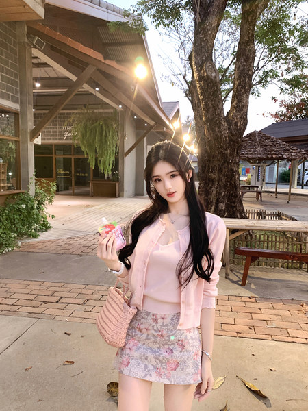 Woman wearing pink cardigan and floral skirt outdoors