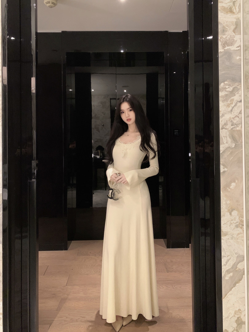 Woman wearing a cream-colored long-sleeve maxi dress with lace detailing on the neckline.
