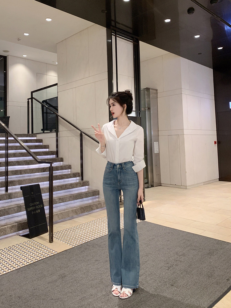 Woman wearing white blouse and blue jeans in a modern indoor setting