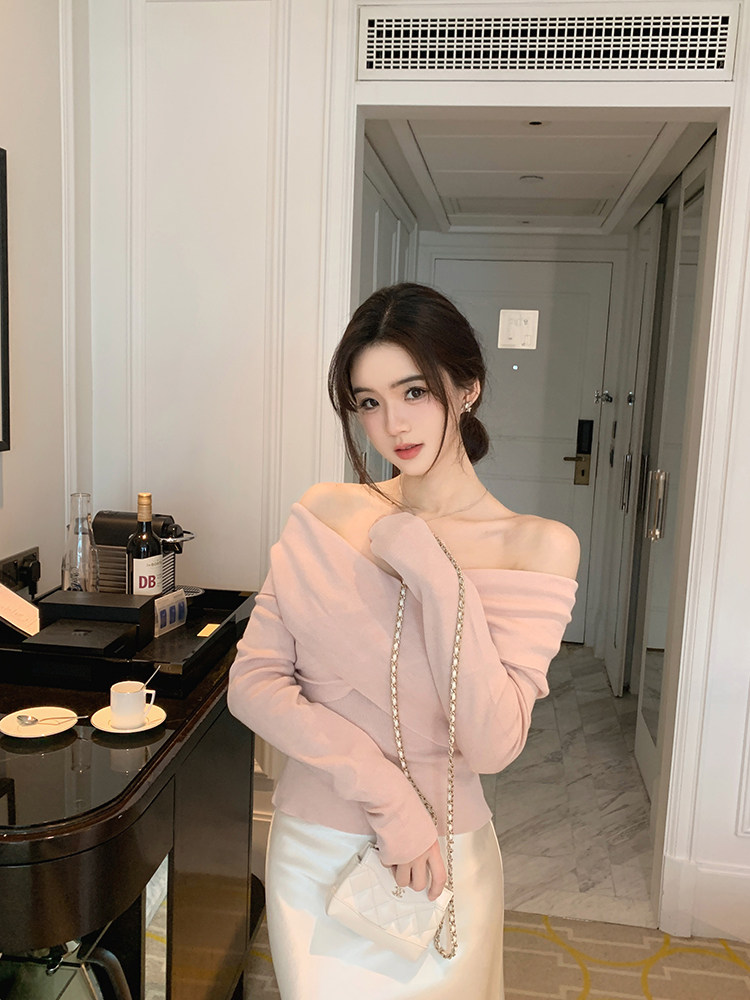 Woman wearing pink off-shoulder top and white skirt with chain-strap bag in hotel room