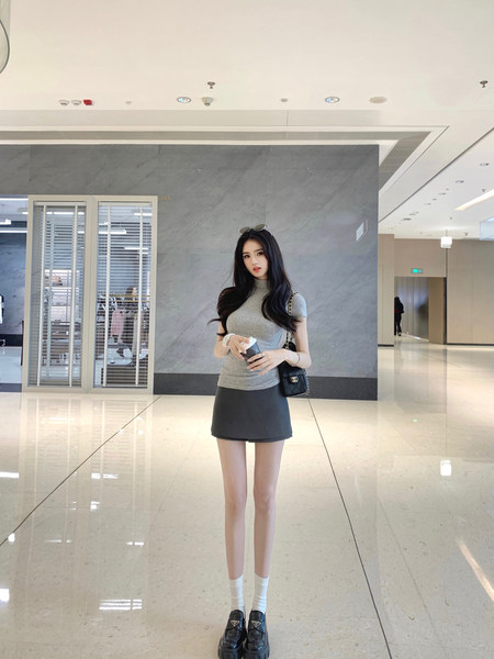 Woman wearing a gray top and black skirt in a modern indoor setting