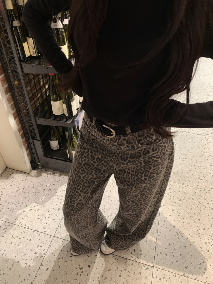 Model wearing leopard print wide-leg pants with black top and belt
