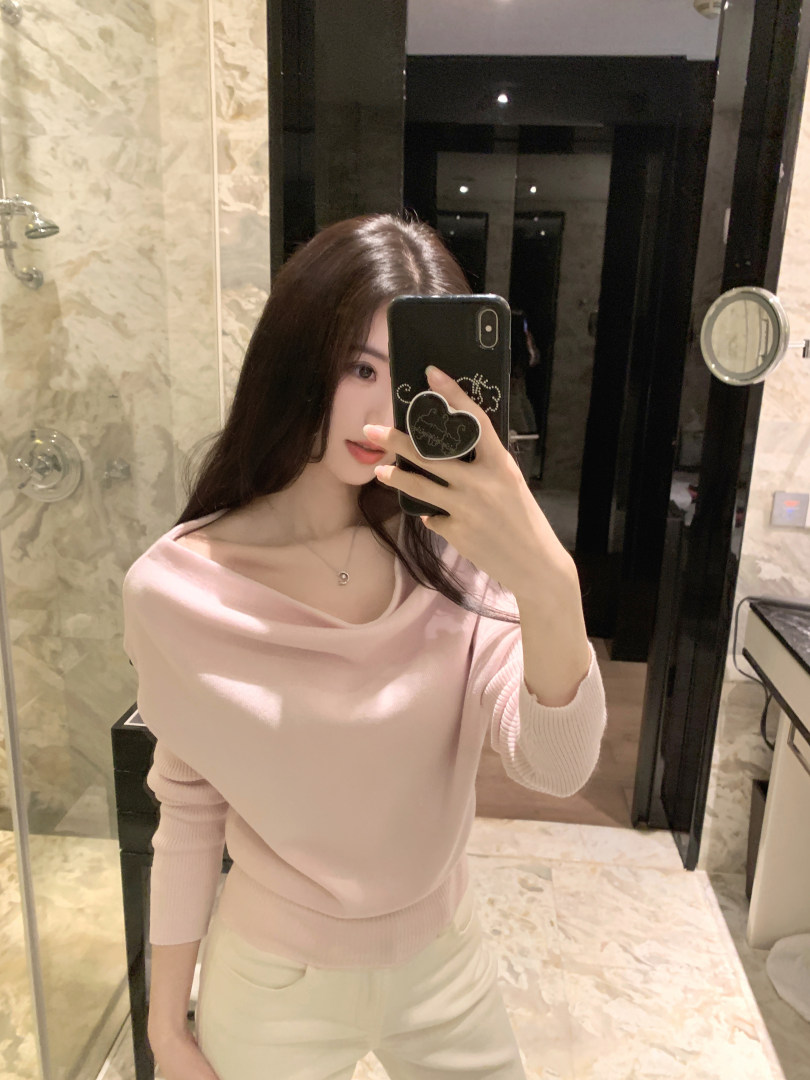 Woman taking mirror selfie wearing a light pink off-shoulder knit top