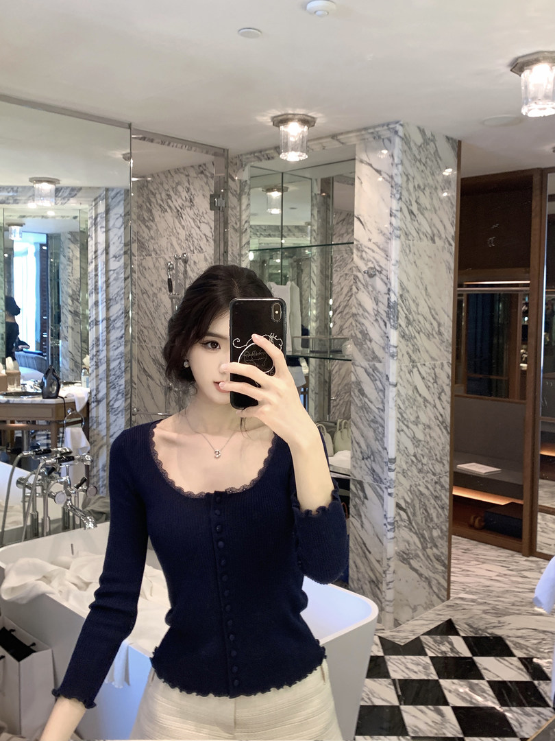 Woman taking mirror selfie wearing navy blue lace-trim cardigan in marble bathroom